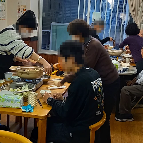 みんなで鍋を囲んでの食事風景写真